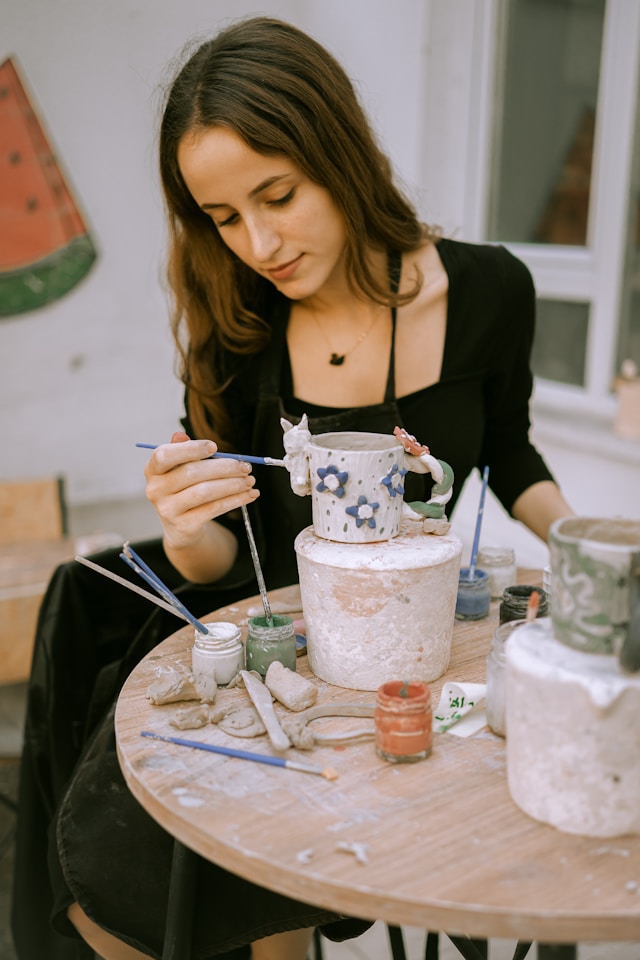a woman painting a mug